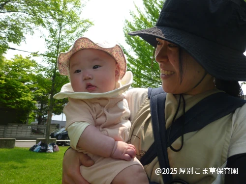 遠足で、たんぽぽ組（０歳児）のお子さまが先生に抱っこしてもらっているかわいい様子