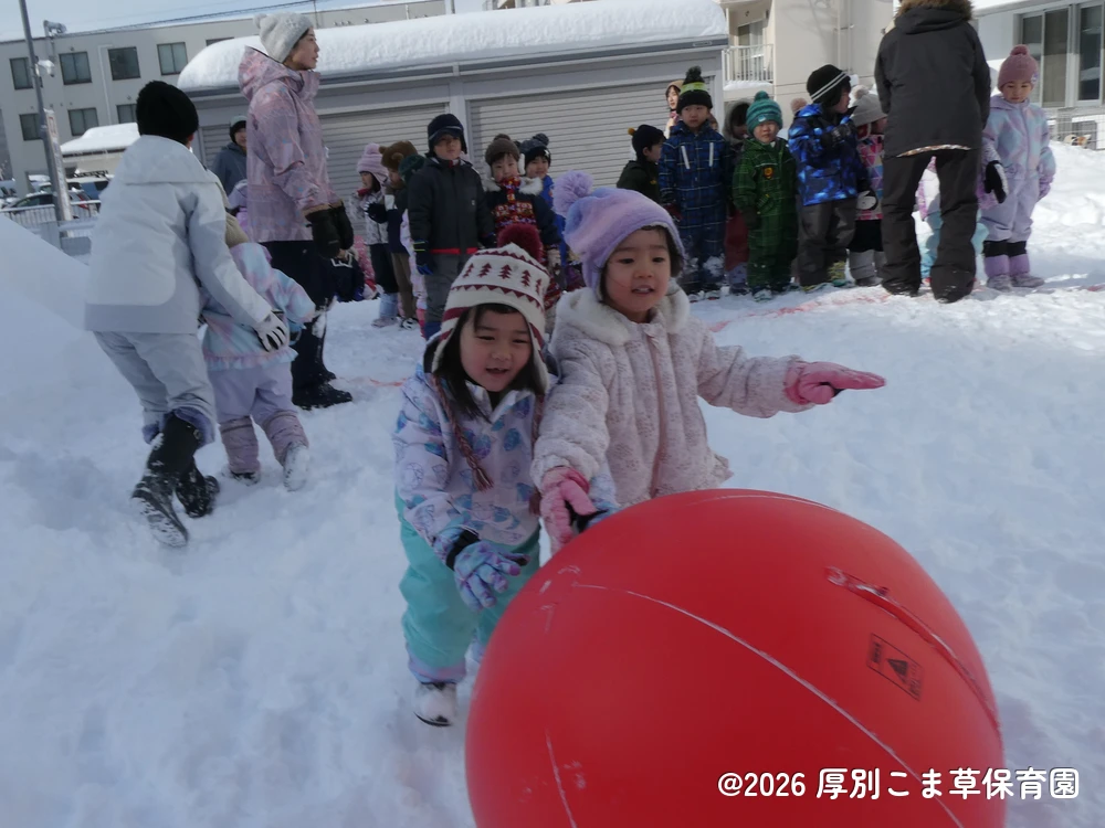 大玉転がしをしているすみれ組（４歳児）とあさがお組（３歳児）ちゅうりっぷ組（２歳児）の子どもたちの様子