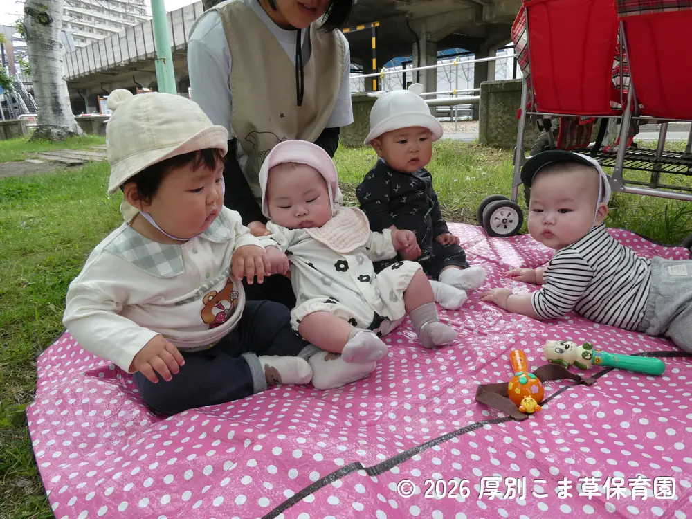 シートの上に座っておもちゃで遊んでいる子どもたちの様子