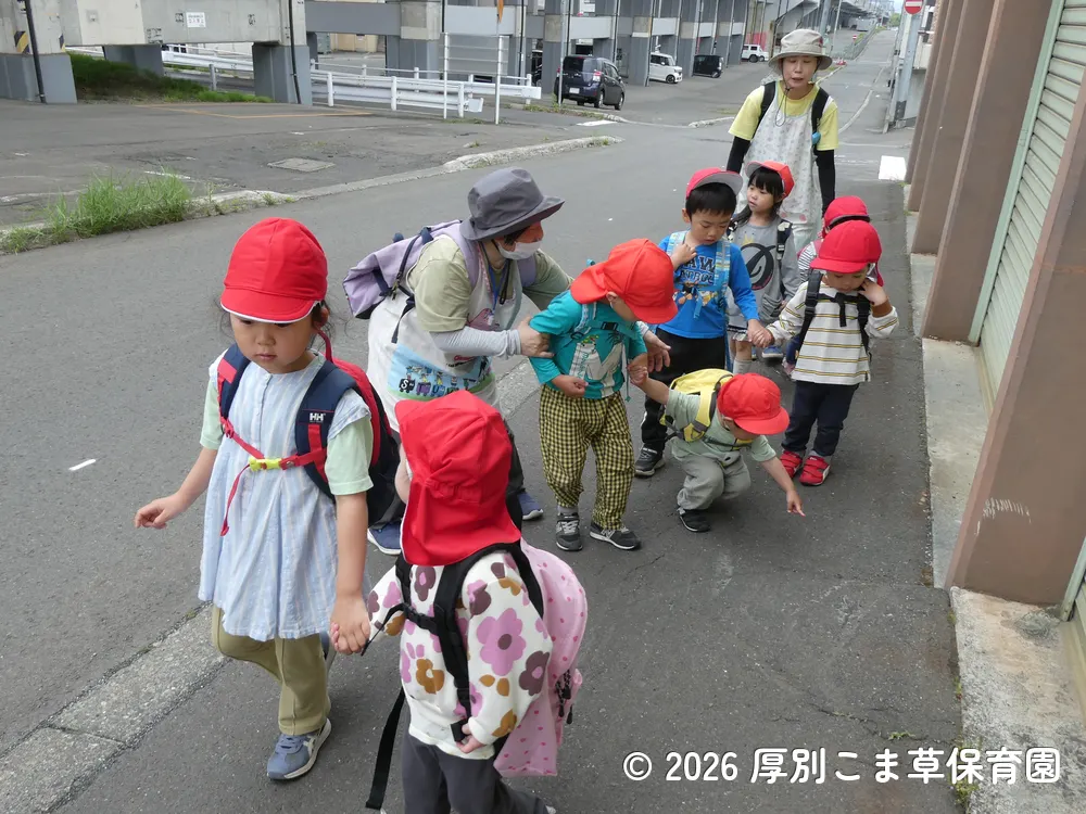 年長児と手をつないで公園へ向かうちゅう子どもたちの様子