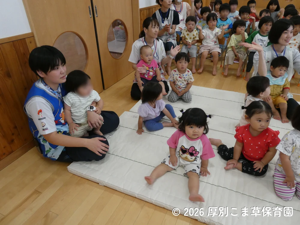 誕生会が始まる前に司会の先生と手遊びをしている子どもたちの様子