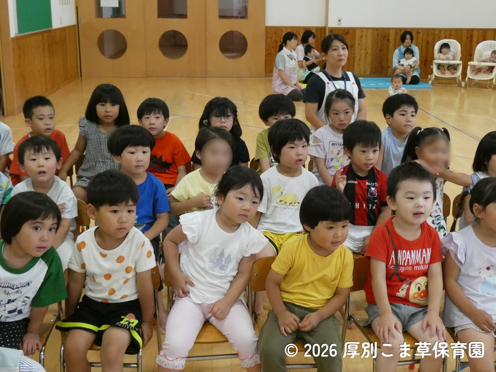 誕生会が始まる前に司会の先生のお話を聞いている子どもたちの様子