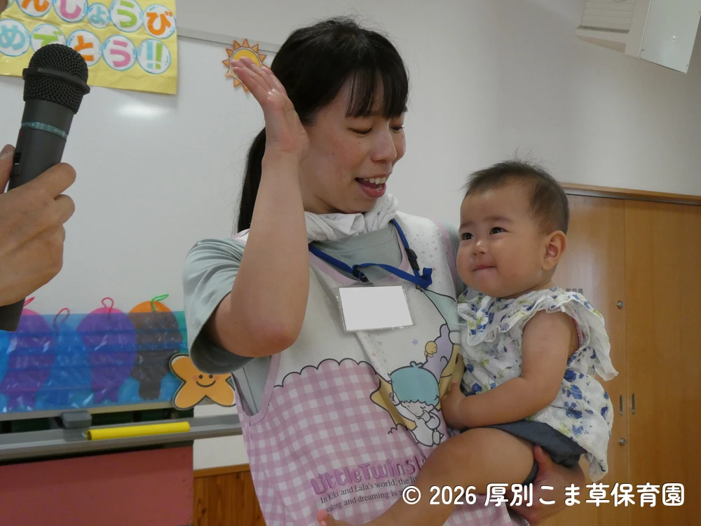 名前を呼ばれて笑顔で応えるたんぽぽ組（０歳児）の子どもの様子