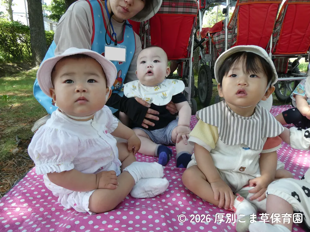木陰の涼しい場所で過ごしているたんぽぽ組（０歳児）の子どもたちの様子