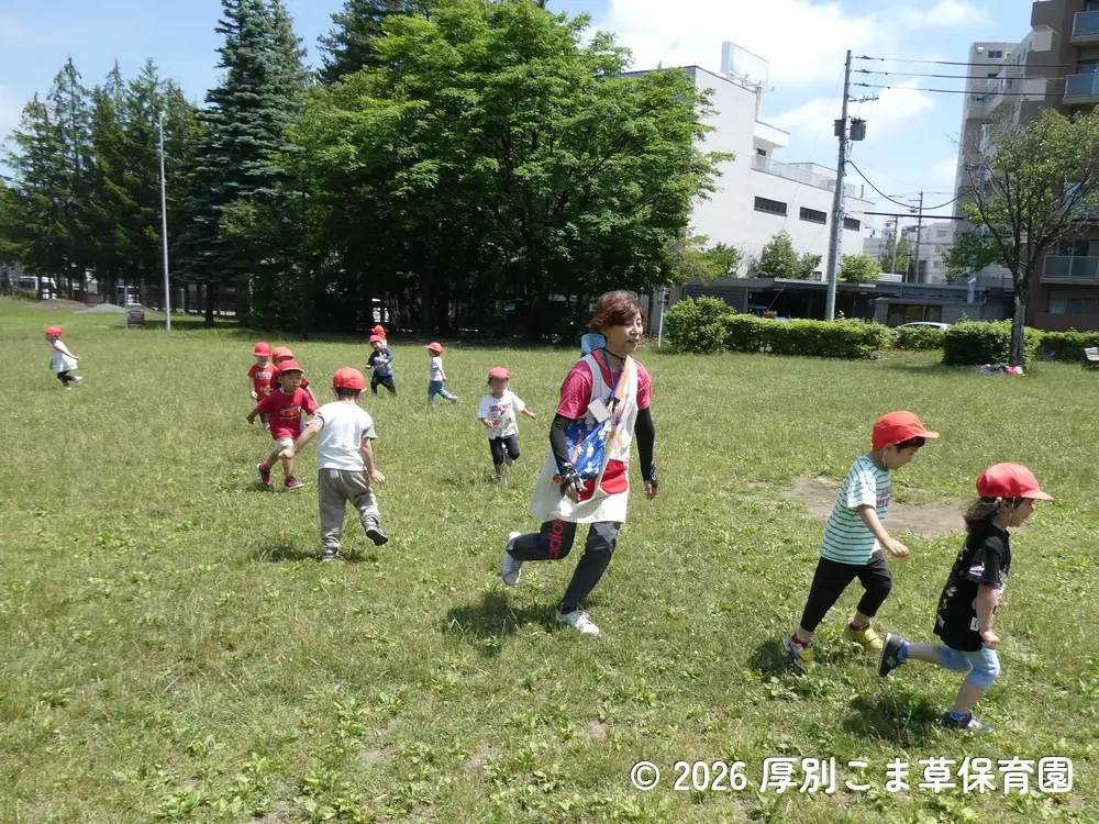 芝生で追いかけっこをしている子どもたちの様子