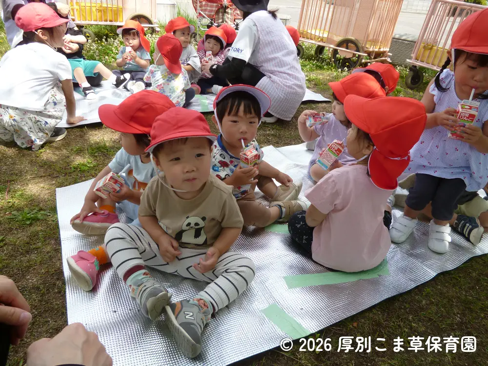公園でジュースを飲んでいるたんぽぽ組（１歳児）の子どもたちの様子