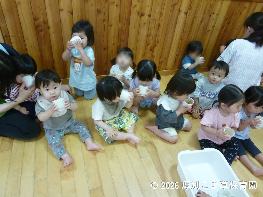 保育園に戻って麦茶を飲んでいるたんぽぽ組（１歳児）の子どもたちの様子