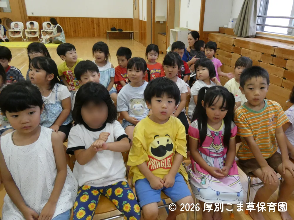 誕生会が始まる前に司会の先生と手遊びをしている子どもたちの様子