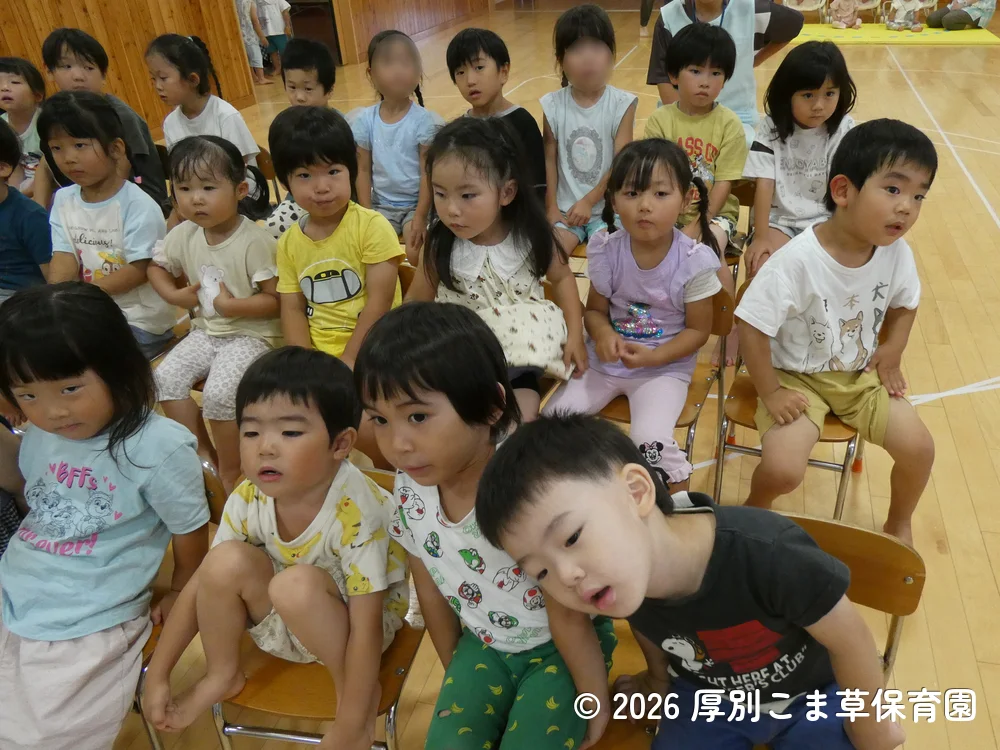 誕生会が始まる前に司会の先生と手遊びをしている子どもたちの様子