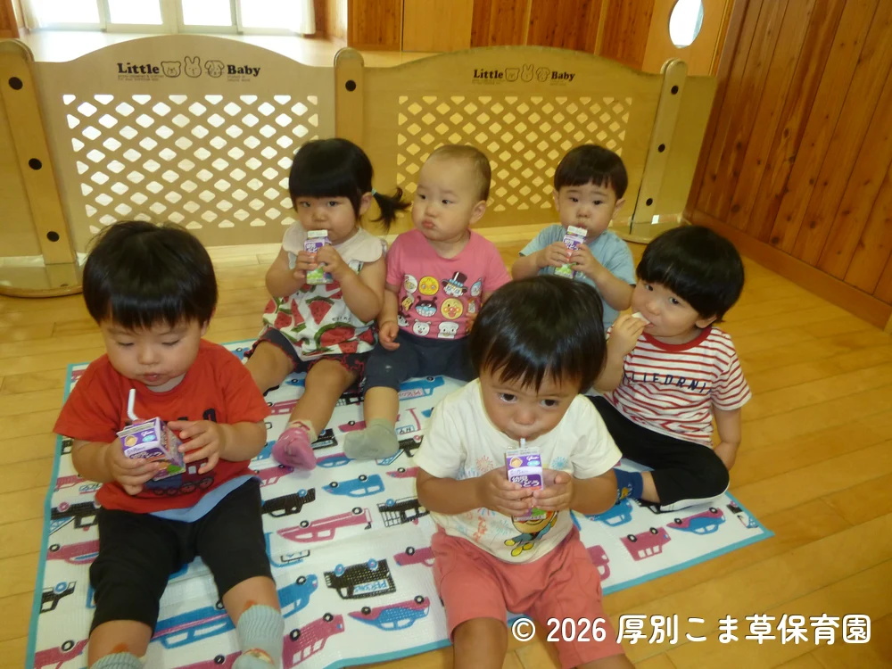 遠足に出発する前に保育園でおやつを食べているたんぽぽ組（１歳児）の子どもたちの様子