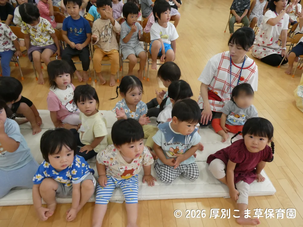 誕生会が始まる前に司会の先生と手遊びをしている子どもたちの様子