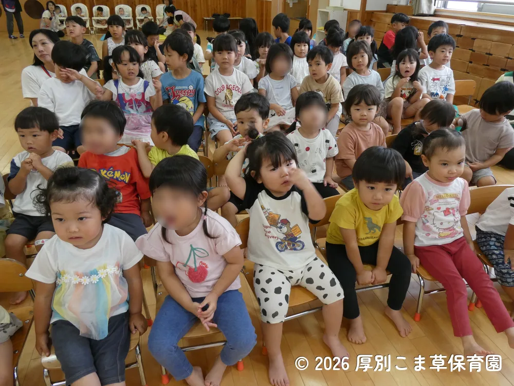 誕生会が始まる前に司会の先生と手遊びをしている子どもたちの様子