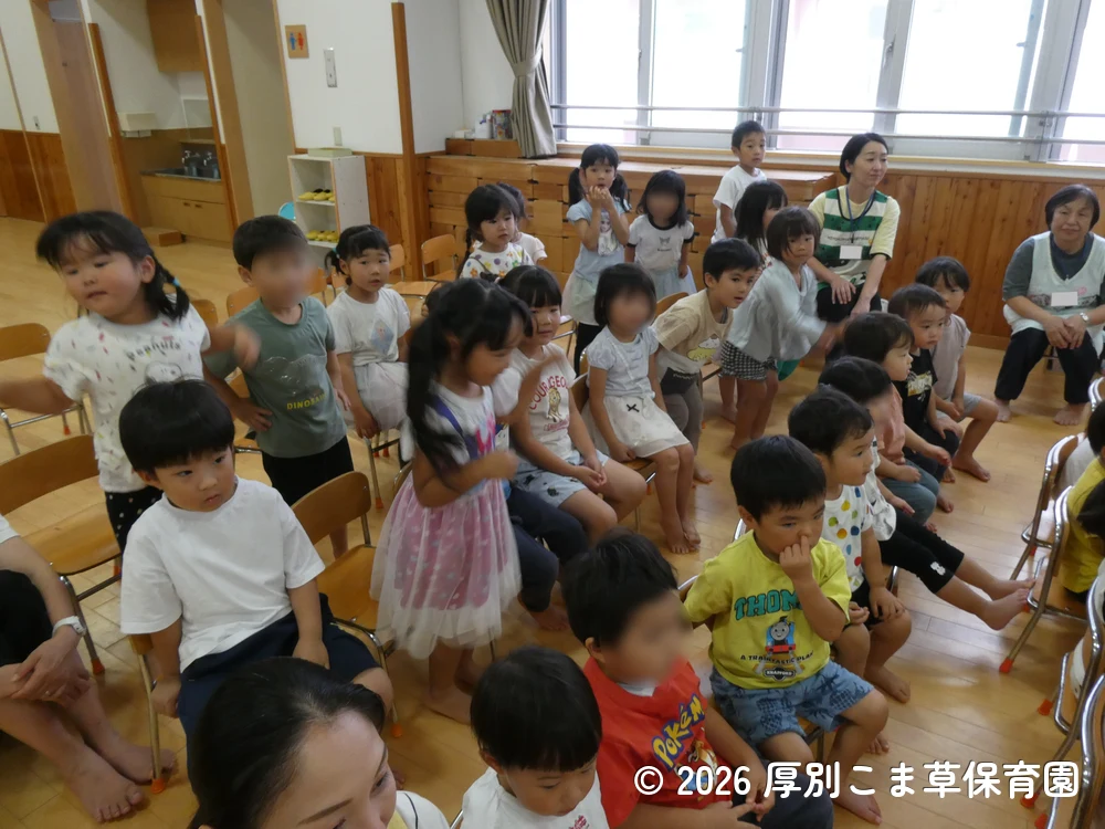 ひまわり組（５歳児）の発表をその場で立ち上がって見入っている子どもたちの様子